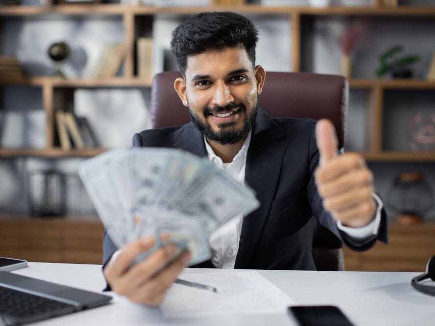 A man holding cash and giving a thumbs up