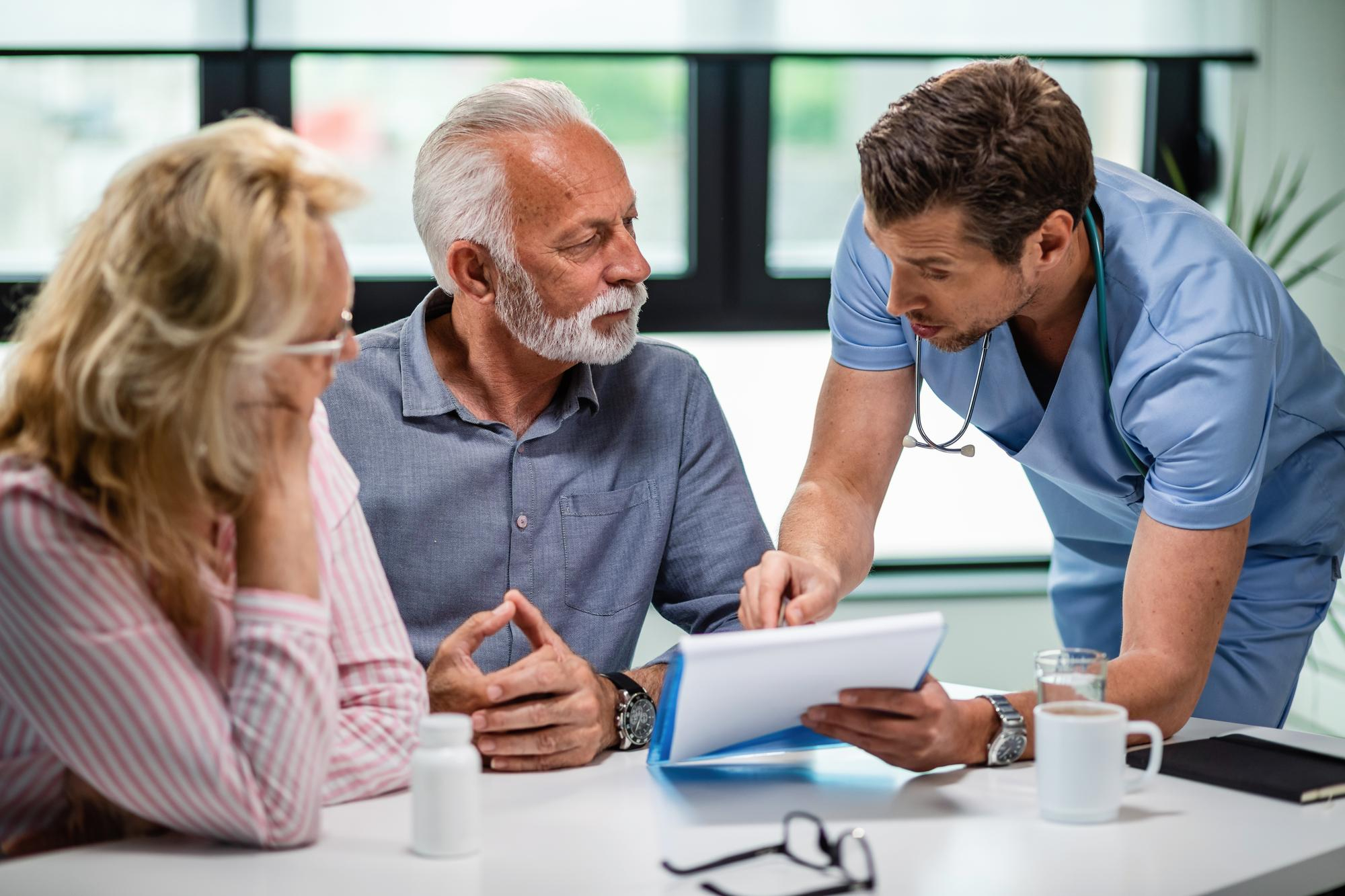A clinician reviewing paperwork with an older couple at a consultation table