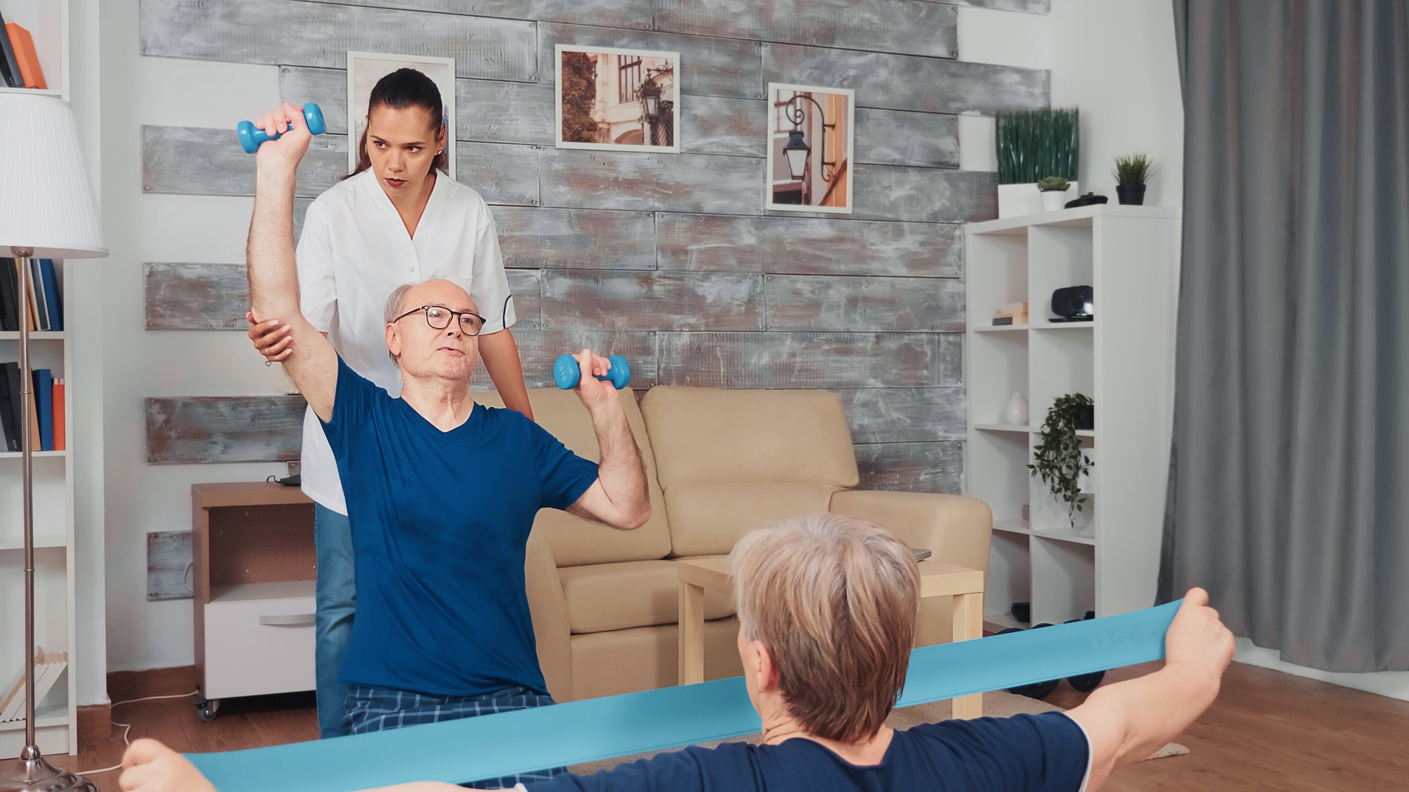 A physiotherapist assisting a patient with a home exercise session using dumbbells and a resistance band